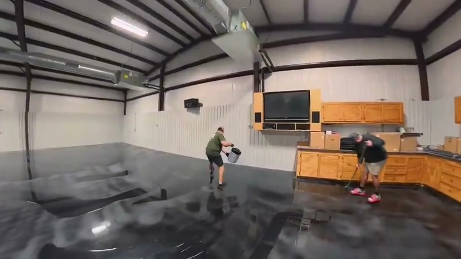 A crew coating the floor of a large steel building