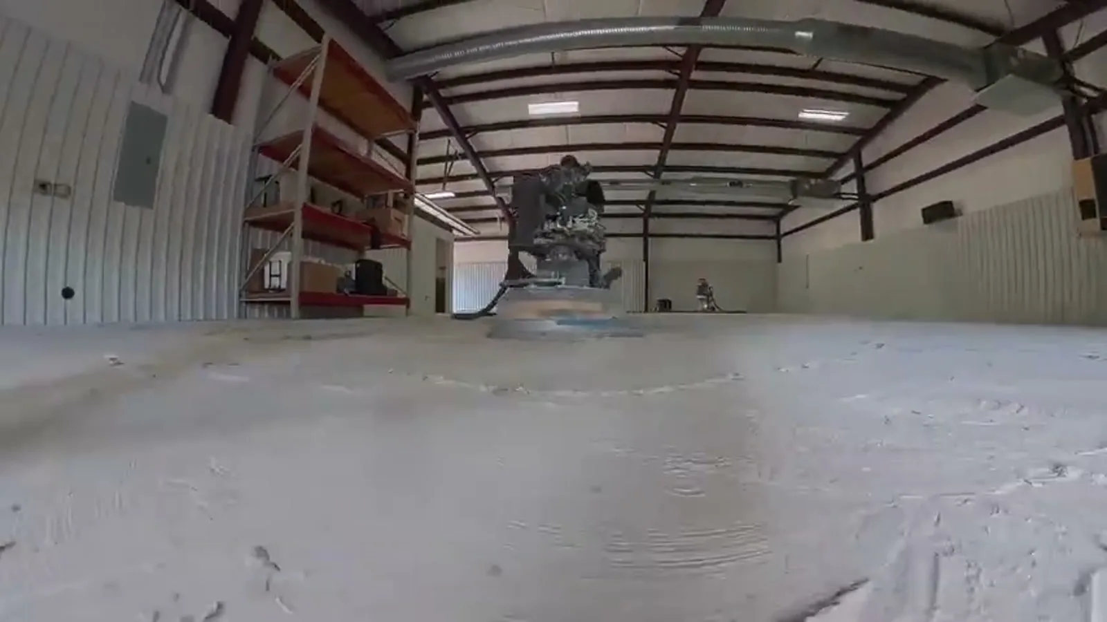 A diamond grinder on a bare concrete slab inside a steel building